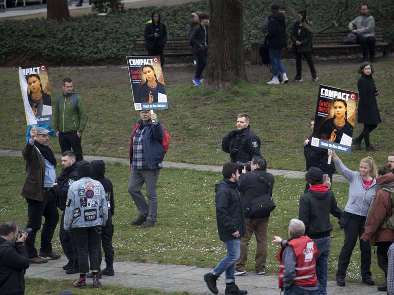 Verstreute Einzelpersonen halten am Rand einer Demonstration Bilder hoch, auf denen die Klimaaktivistin Greta Thunberg und der Schriftzug "Greta nervt" zu sehen ist.
