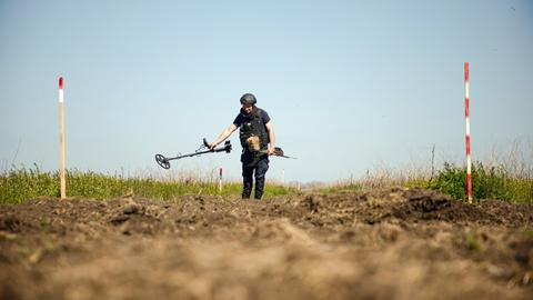 Eine Person von einem Minenräumkommando tastet den Boden während einer Minenräummission in der Region Mykolajiw (Ukraine) am 17. April 2025 mit einem Metalldetektor ab. 
