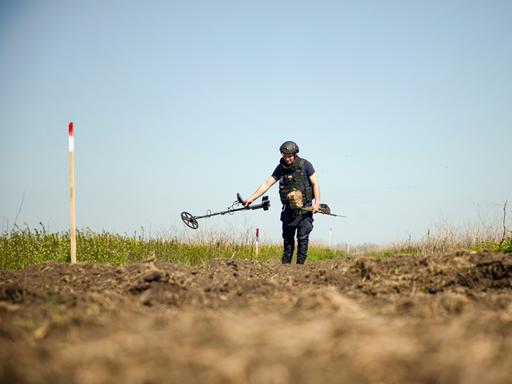 Eine Person von einem Minenräumkommando tastet den Boden während einer Minenräummission in der Region Mykolajiw (Ukraine) am 17. April 2025 mit einem Metalldetektor ab. 