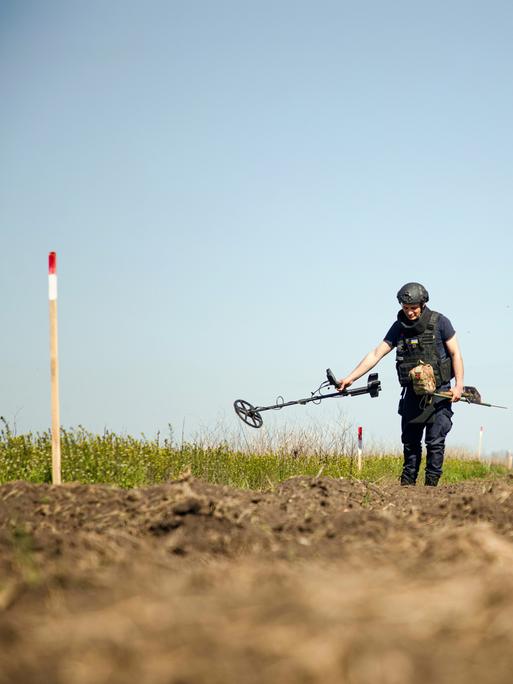 Eine Person von einem Minenräumkommando tastet den Boden während einer Minenräummission in der Region Mykolajiw (Ukraine) am 17. April 2025 mit einem Metalldetektor ab. 