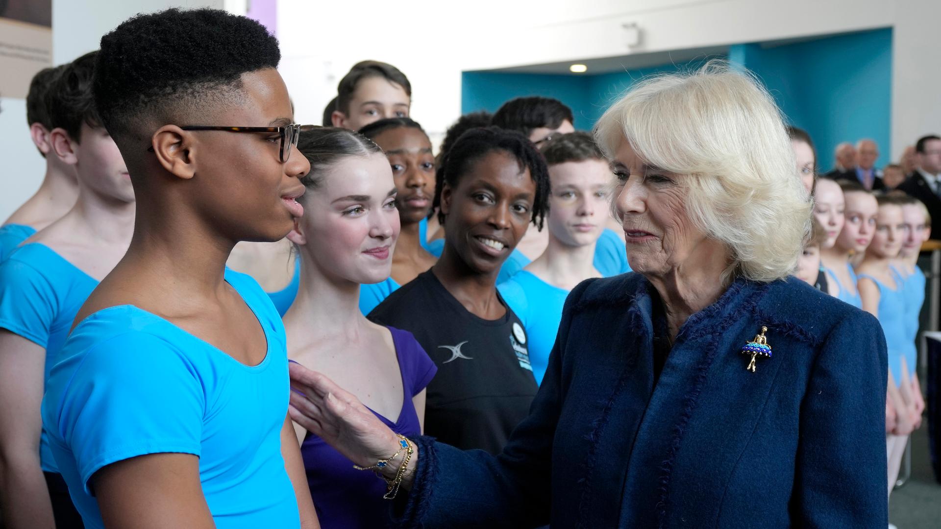 Königin Camila begrüßt den 13-jährigen Balletttänzer Anthony Madu aus Nigeria. Er lächelt leicht verlegen, sie freundlich.