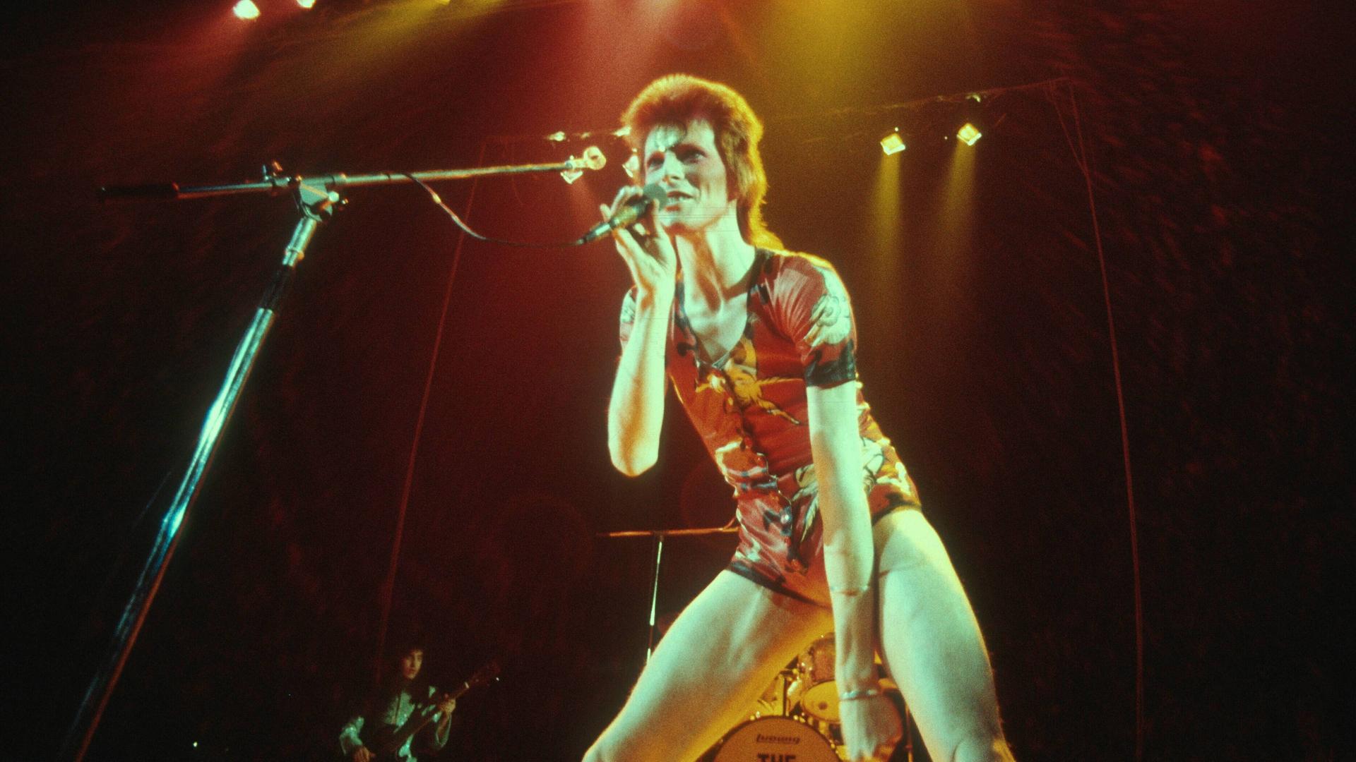 David Bowie als Ziggy Stardust im Jahr 1972 uf der Bühne mit roten Haaren. David Bowie als Ziggy Stardust im Jahr 1972 uf der Bühne mit roten Haaren.