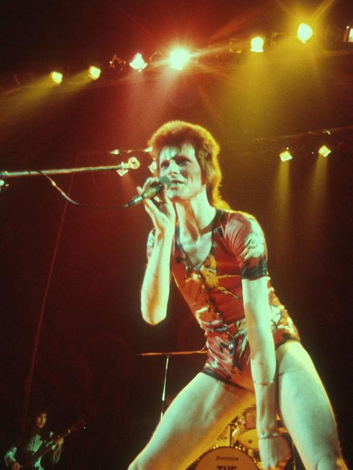 David Bowie als Ziggy Stardust im Jahr 1972 uf der Bühne mit roten Haaren.