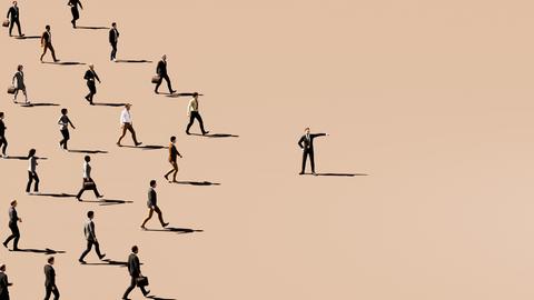 Illustration eines Unternehmensleiters, der in eine Richtung zeigt, während eine große Gruppe von Geschäftsleuten zielstrebig hinter ihm hergeht, vor einem hellbraunen Hintergrund. 