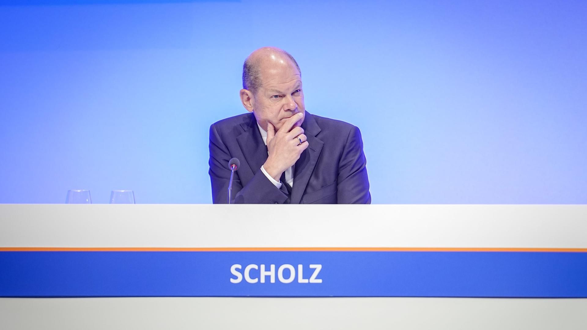Bundeskanzler Olaf Scholz (SPD) sitz auf einem Podium. Bundeskanzler Olaf Scholz (SPD) sitz auf einem Podium.