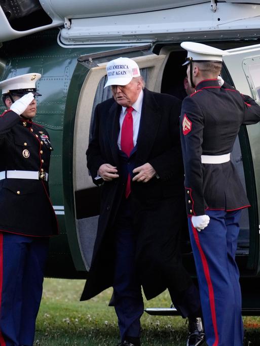 US-Präsident Donald Trump bei seiner Ankunft beim G7-Gipfel in Kananaskis, Alberta ein. Er steigt aus einem Hubschrauber und wird von zwei kanadischen Militärs begrüßt.