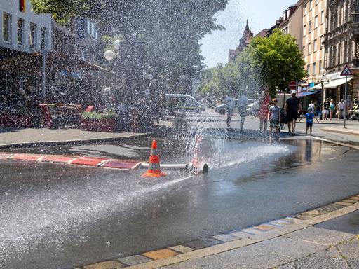 Über einen geöffneten Feuerwehrschlauch der Berufsfeuerwehr Nürnberg am Jakobsplatz wird Wasser zum Abkühlen versprüht bei sommerlicher Hitze. 