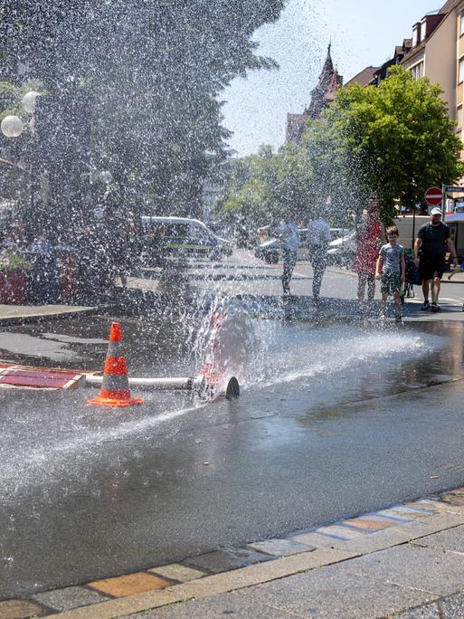 Über einen geöffneten Feuerwehrschlauch der Berufsfeuerwehr Nürnberg am Jakobsplatz wird Wasser zum Abkühlen versprüht bei sommerlicher Hitze. Über einen geöffneten Feuerwehrschlauch der Berufsfeuerwehr Nürnberg am Jakobsplatz wird Wasser zum Abkühlen versprüht bei sommerlicher Hitze.