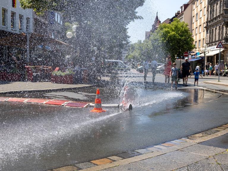 Über einen geöffneten Feuerwehrschlauch der Berufsfeuerwehr Nürnberg am Jakobsplatz wird Wasser zum Abkühlen versprüht bei sommerlicher Hitze. Über einen geöffneten Feuerwehrschlauch der Berufsfeuerwehr Nürnberg am Jakobsplatz wird Wasser zum Abkühlen versprüht bei sommerlicher Hitze.