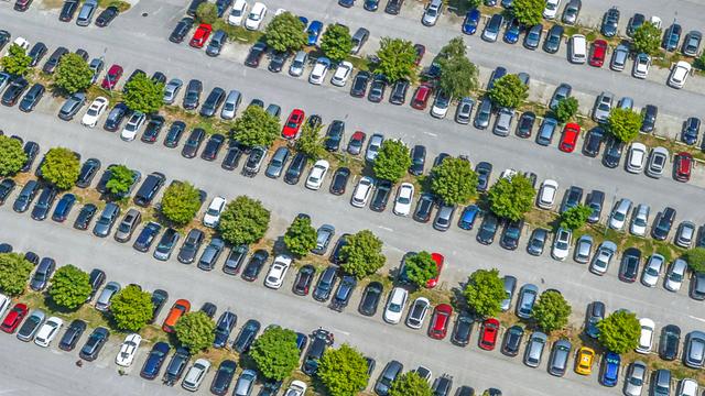  Blick von oben auf einen mit Autos komplett belegten Parkplatz.