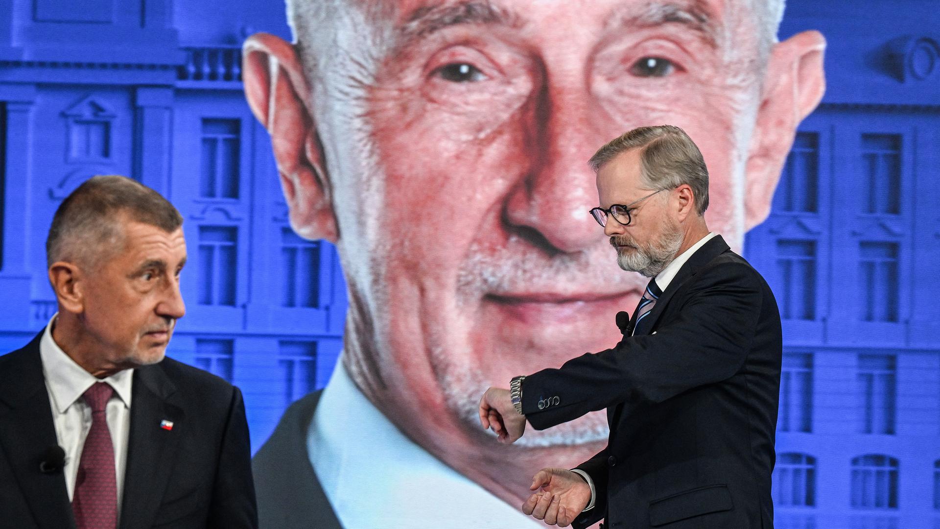 Andrej Babis und Petr Fiala stehen bei einer TV-Wahlkampfveranstaltung vor einem Studiohintergrund mit einem riesigen Porträt von Andrej Babis.