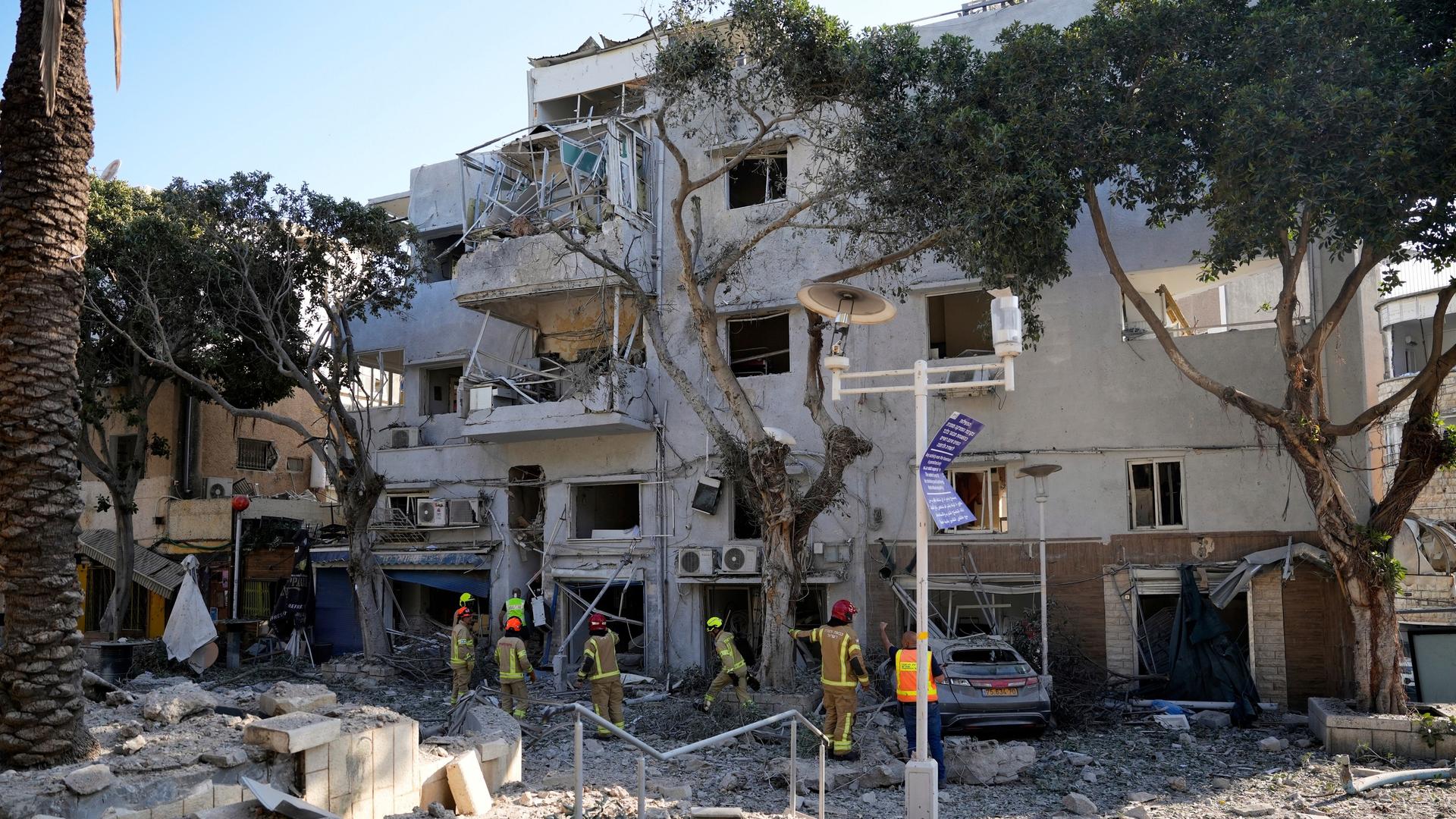 Feuerwehrleute stehen vor einem von Raketen getroffenen Gebäude in der israelischen Stadt Haifa. Feuerwehrleute stehen vor einem von Raketen getroffenen Gebäude in der israelischen Stadt Haifa.