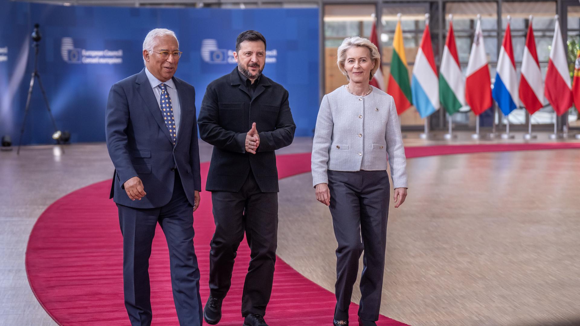 EU-Ratspräsident Costa, Präsident Selenskyj und EU-Kommissionspräsidentin von der Leyen gehen nebeneinander über einen roten Teppich.