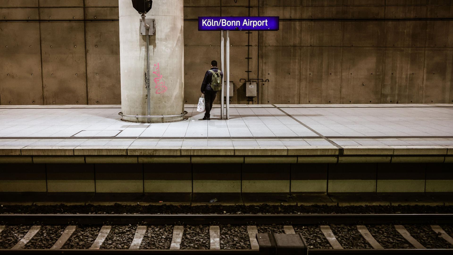 Ein Mann steht allein am Flughafenbahnhof auf dem Bahnsteig.