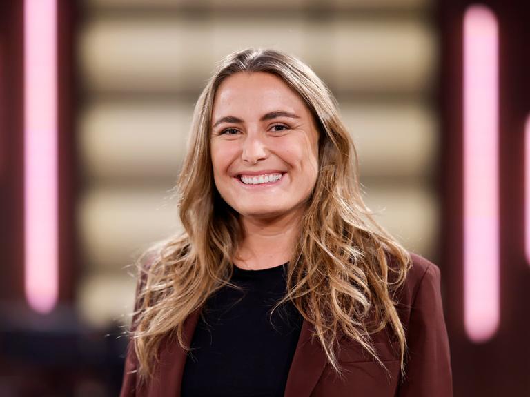 Nathalie Pohl steht in einem Fernsehstudio und lacht in die Kamera