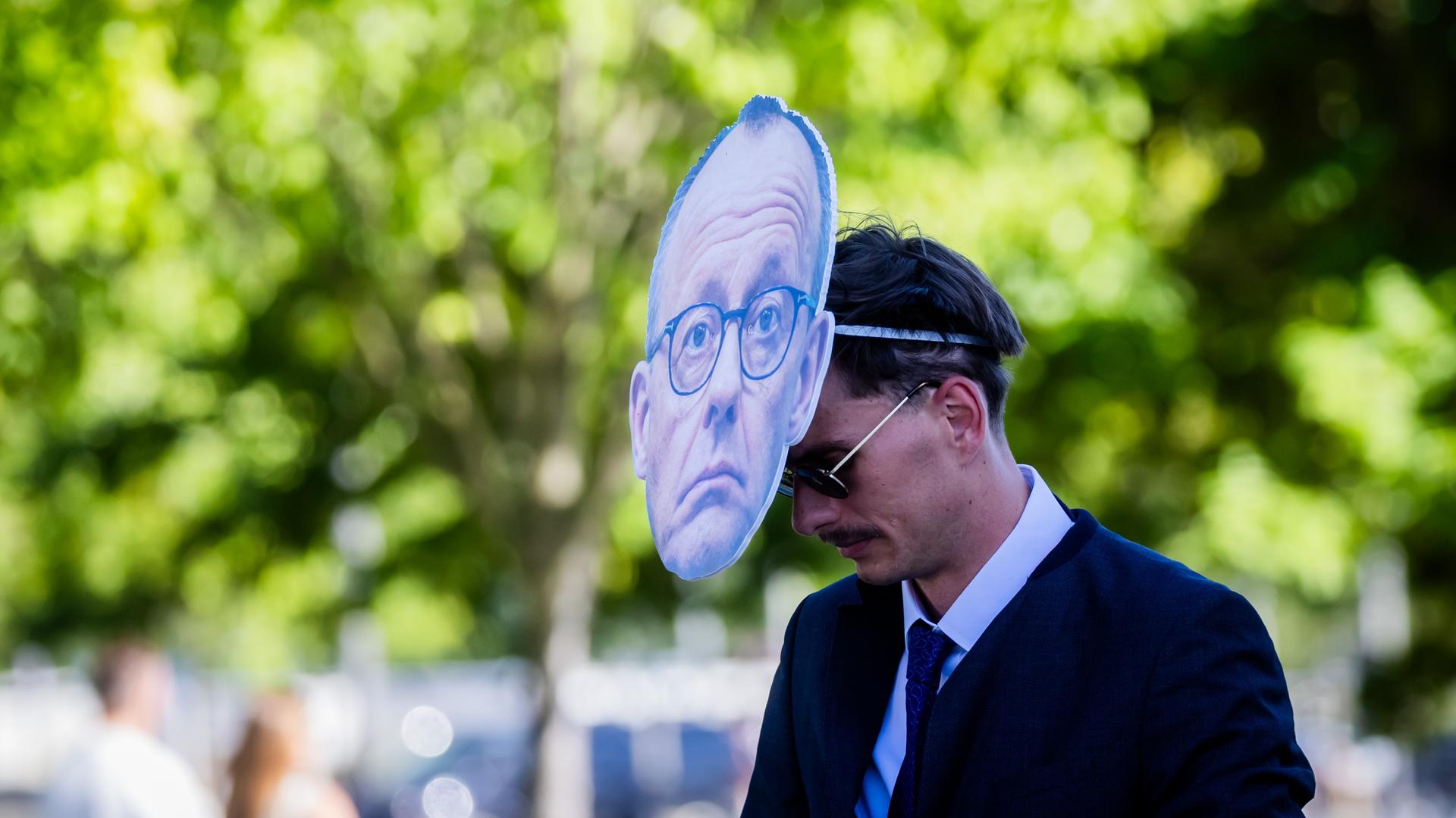 Der Mann trägt eine Maske, die das Gesicht des Bundeskanzlers zeigt. Man sieht ihn von der Seite und deshalb auch sein Gesicht. Der Mann trägt eine Maske, die das Gesicht des Bundeskanzlers zeigt. Man sieht ihn von der Seite und deshalb auch sein Gesicht.