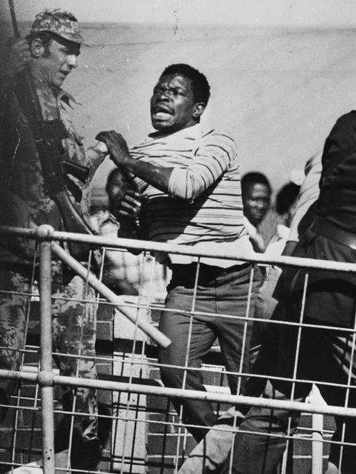 Während eines Anti-Apartheid Protests im Soweto Township in Südafrika rennt einer der Protestierenden in Richtung einer Absperrung während Polizisten und Soldaten versuchen, ihn aufzuhalten.