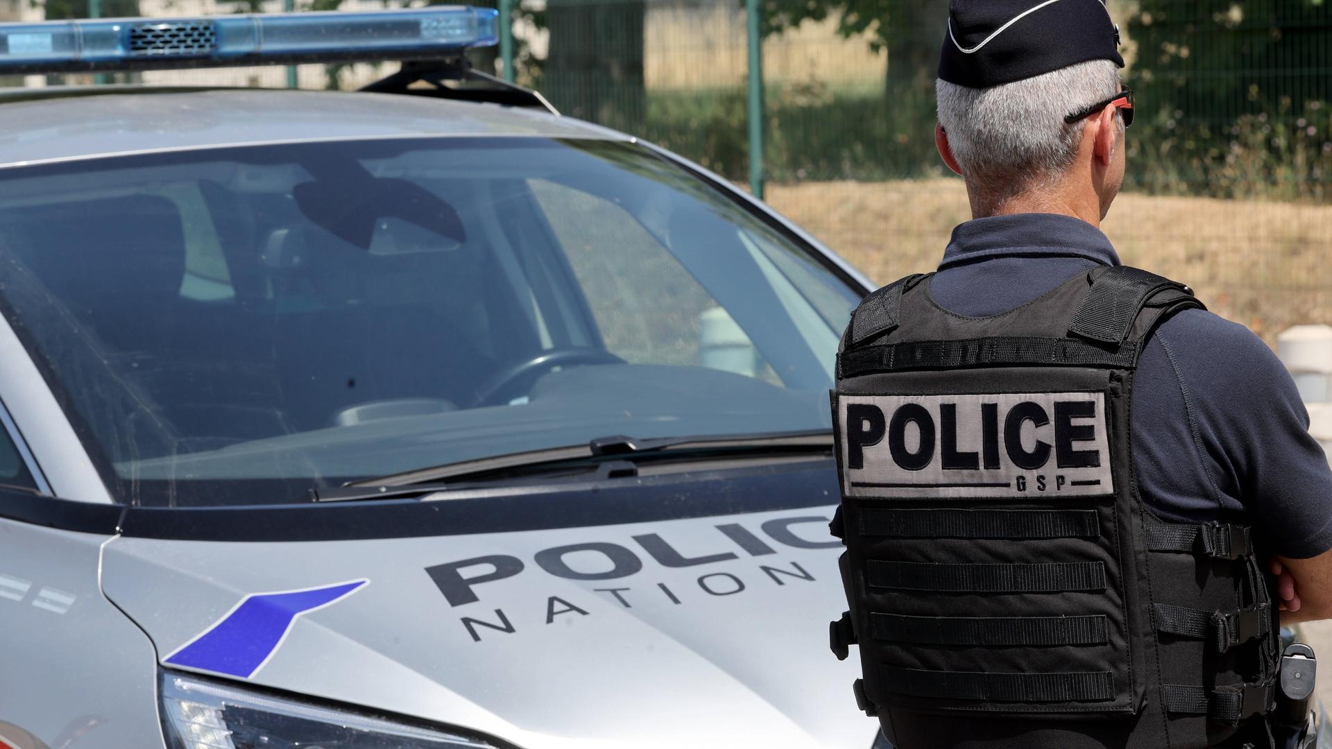 französischer Polizist vor Polizeiauto französischer Polizist vor Polizeiauto