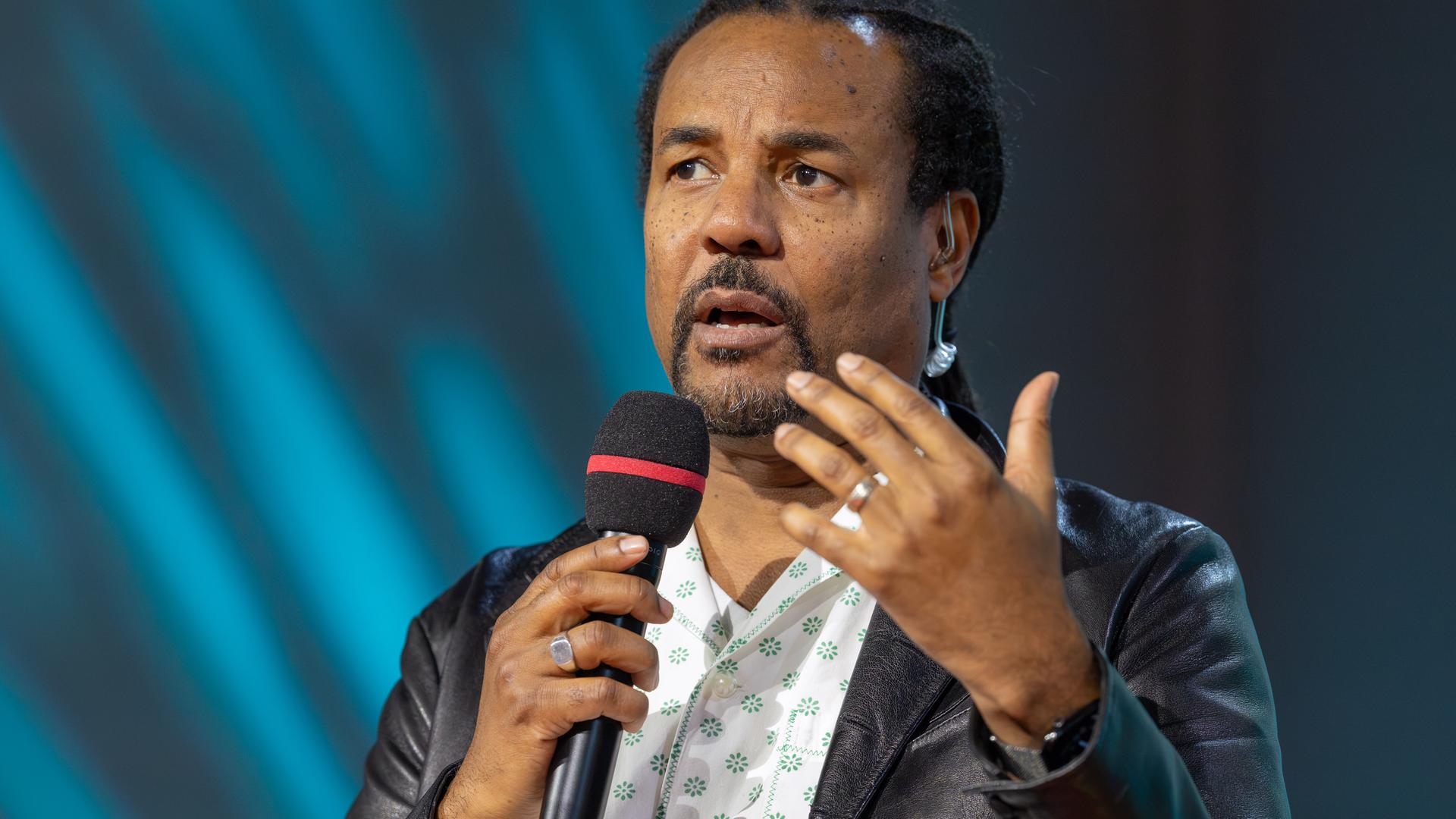 Colson Whitehead bespricht auf der Literaturbühne von ARD, ZDF und 3sat sein neues Buch "Cool Machine" und hält ein Mikrofon in der Hand.