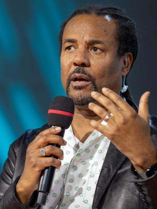 Colson Whitehead bespricht auf der Literaturbühne von ARD, ZDF und 3sat sein neues Buch "Cool Machine" und hält ein Mikrofon in der Hand.