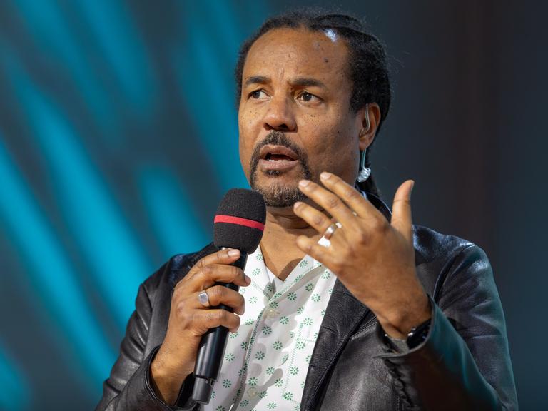 Colson Whitehead bespricht auf der Literaturbühne von ARD, ZDF und 3sat sein neues Buch "Cool Machine" und hält ein Mikrofon in der Hand.