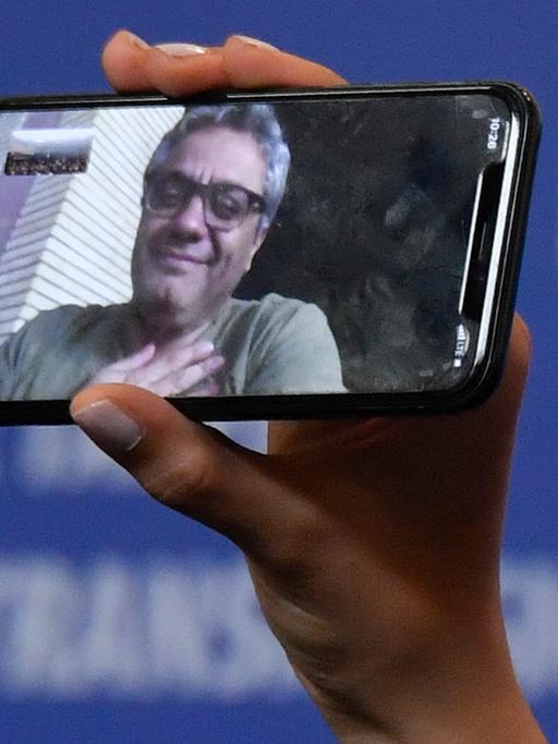 Das Foto zeigt ein Handy, darauf ist der iranische Regisseur Mohammed Rassulof zu sehen. 