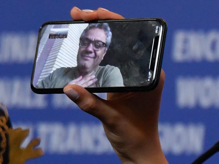 Das Foto zeigt ein Handy, darauf ist der iranische Regisseur Mohammed Rassulof zu sehen. 