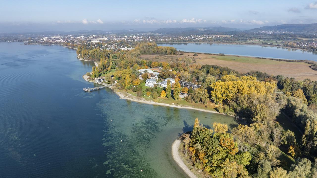 Luftbild von der Halbinsel Mettnau, umgeben mit herbstlicher Vegetation, im westlichen Bodensee mit dem Kurzentrum, Mettnaukur, Schiffanlegestelle und Restaurant Strandcafe, Radolfzell, Landkreis Konstanz, Baden-Württemberg, Deutschland