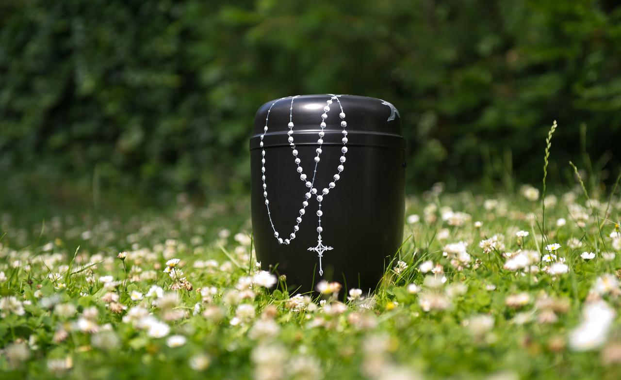 Eine von der Künstlerin Antje Homrighausen bemalte Urne mit Rosenkranzmotiv auf einer Wiese. Eine von der Künstlerin Antje Homrighausen bemalte Urne mit Rosenkranzmotiv auf einer Wiese.