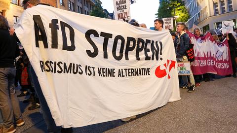 Teilnehmer einer Demonstration gegen Rechts halten ein Banner mit der Aufschrift "AfD stoppen! Rassismus ist keine Alternative".