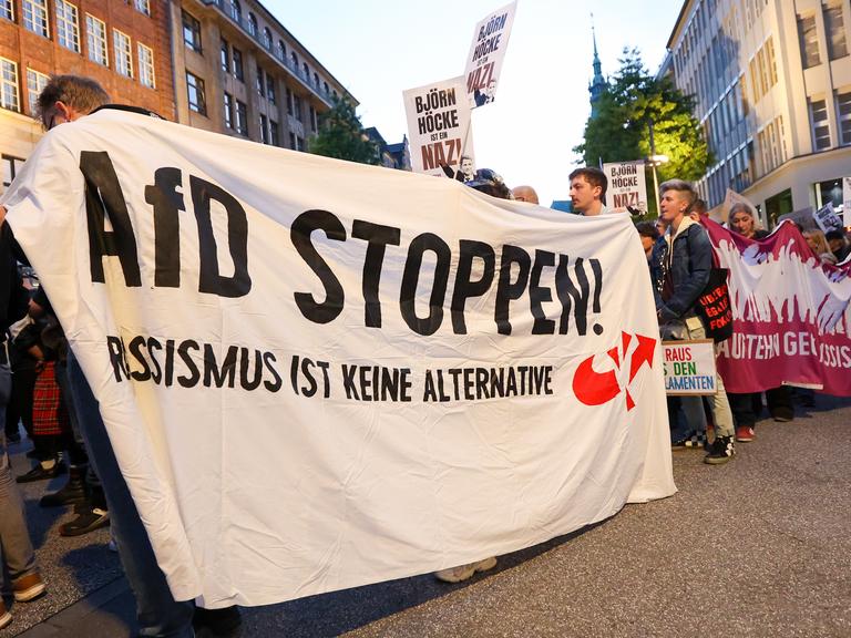 Teilnehmer einer Demonstration gegen Rechts halten ein Banner mit der Aufschrift "AfD stoppen! Rassismus ist keine Alternative".