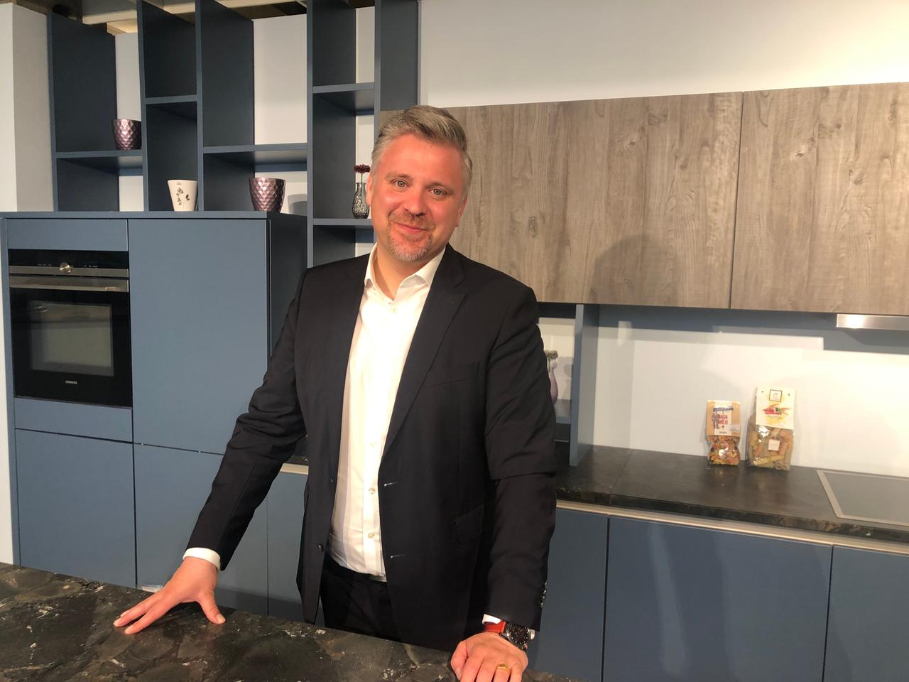 Volker Irle, Geschäftsführer AMK, steht in einer neuen Einbauküche.