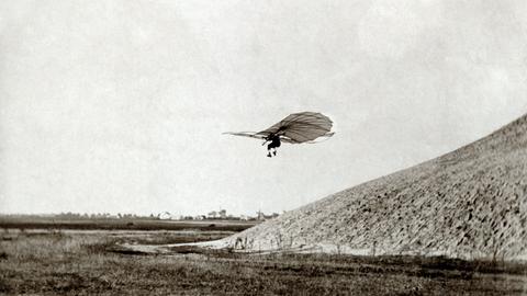 Flugpionier Otto Lilienthal fliegt mit einem Gleitflieger im 19. Jahrhundert von einem Hügel herunter. Flugpionier Otto Lilienthal fliegt mit einem Gleitflieger im 19. Jahrhundert von einem Hügel herunter.