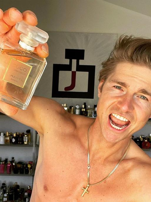 Ein Selfie von Jeremy Fragrance von seinem Social Media Account, er hält eine Parfümflasche in die Kamera und hat einen trainierten Oberkörper.
