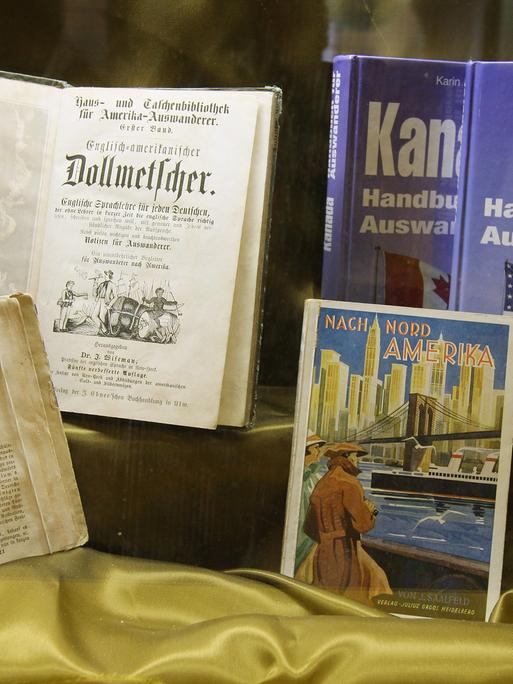 Ein Exponat zeigt Handbücher für Auswanderer nach Amerika aus verschiedenen Epochen im Auswanderermuseum BallinStadt in Hamburg.
