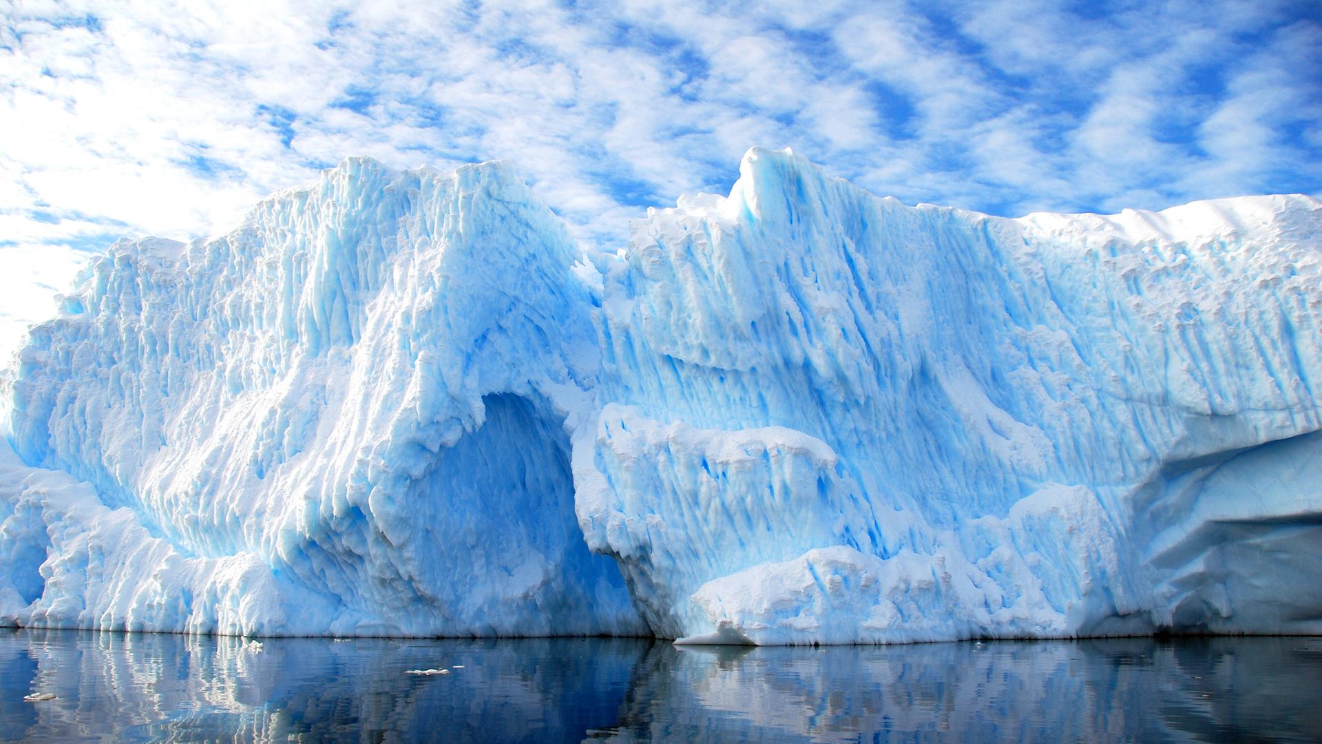 Ein Eisberg spiegelt sich im Wasser.