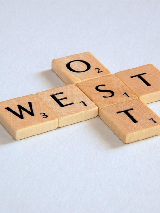 "Ost" und "West" - Schriftzug aus Scrabblesteinen.