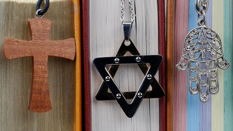Religiöse Symbole: Christliches Kreuz, Davidstern und Hand von Fatima stehen für Christentum, Islam und Judentum