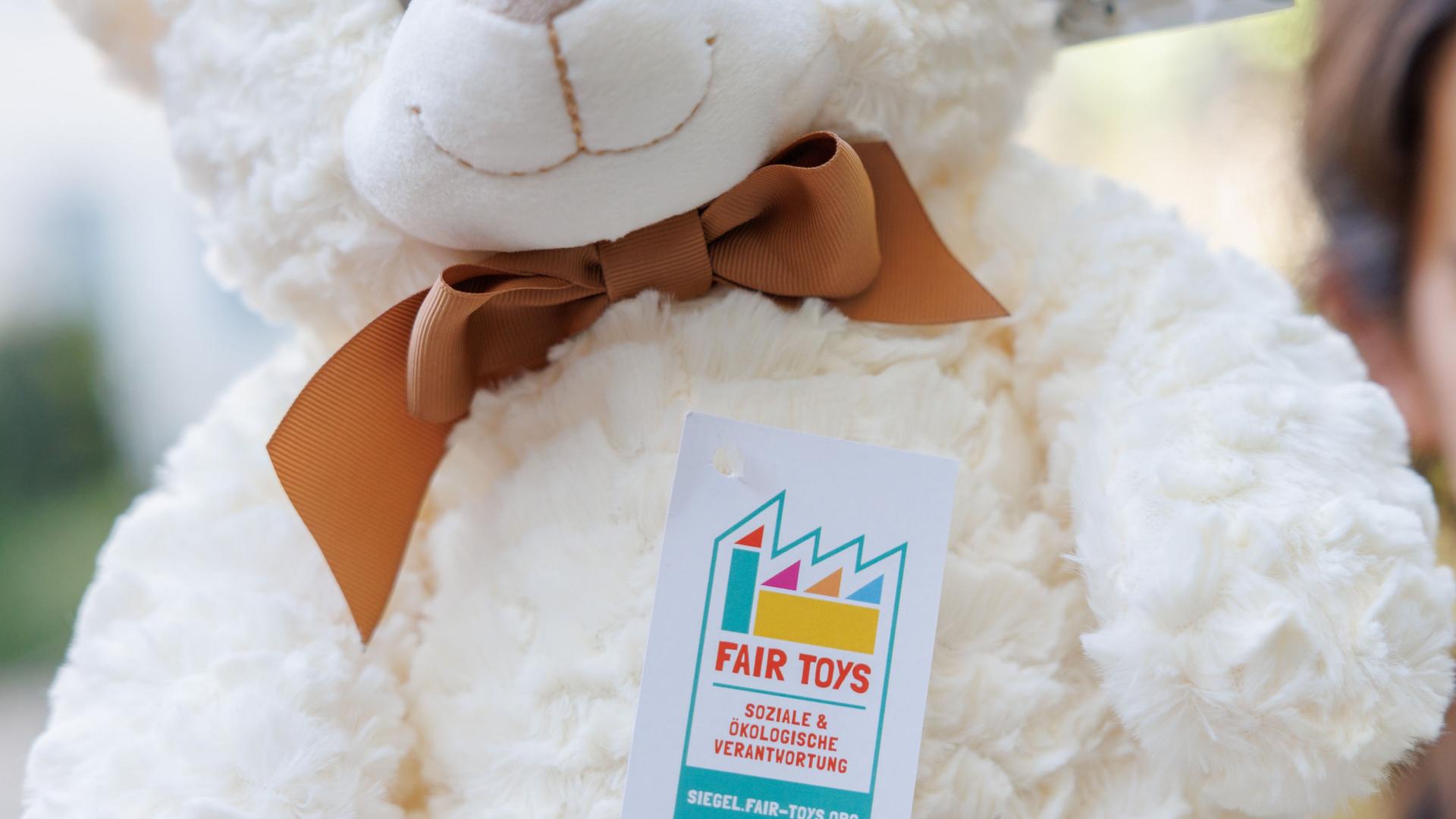 Ein Plüschbär, der mit dem Fair Toys Siegel für faires Spielzeug gekennzeichnet ist.