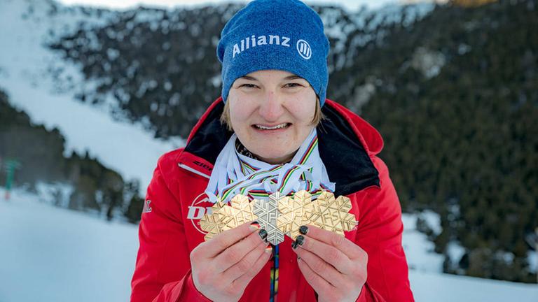 Anna-Lena Forster hält vier Goldmedaillen in die Kamera.