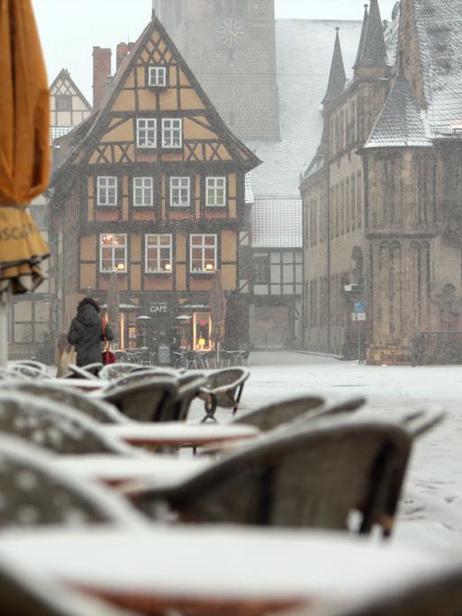 Schneebedeckt sind die Tische eines Straßencafés auf dem Marktplatz eines Ortes im Harz.