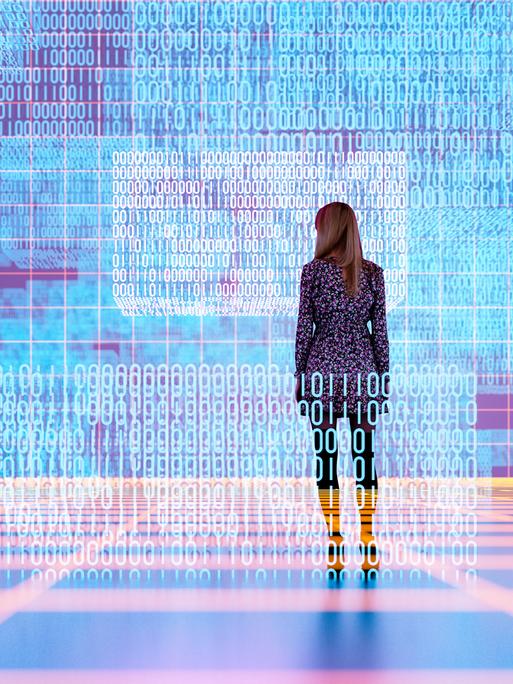 Eine weibliche Persons steht in einem digitalen Raum und schaut auf zahlreiche Coding-Reihen
