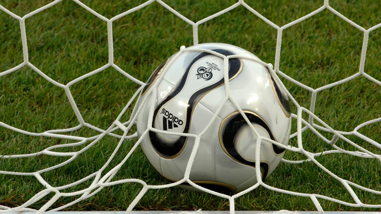 Ein Ball mit dem Logo der Fußball-WM 2006 liegt im Tornetz auf dem Rasen.