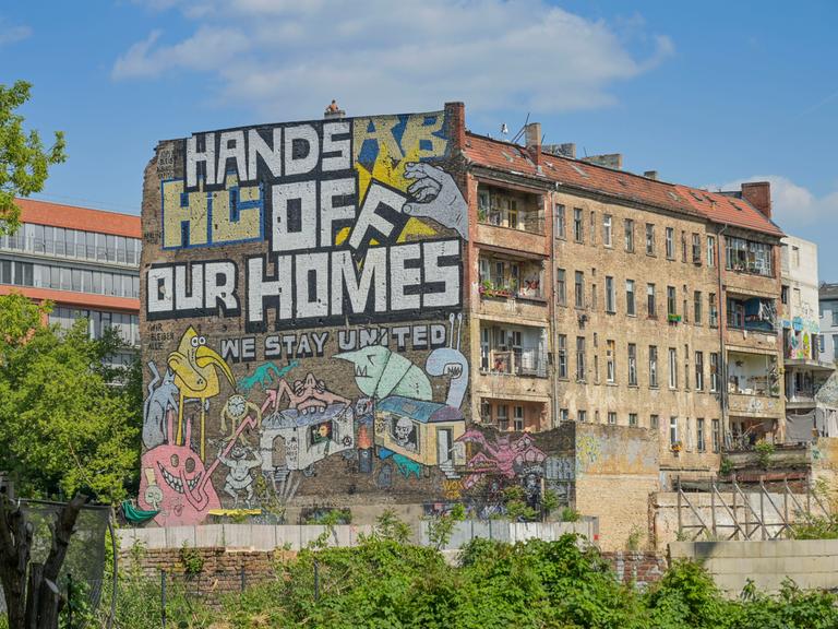 Auf der Fassade des autonomen Hausprojektes Köpi in Berlin ist zu lesen: Hands off our homes! We stay united.