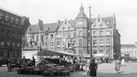 Gemüsemarkt in Düsseldorf in den 1930er-Jahren, gesäumt von Hakenkreuzfahnen.