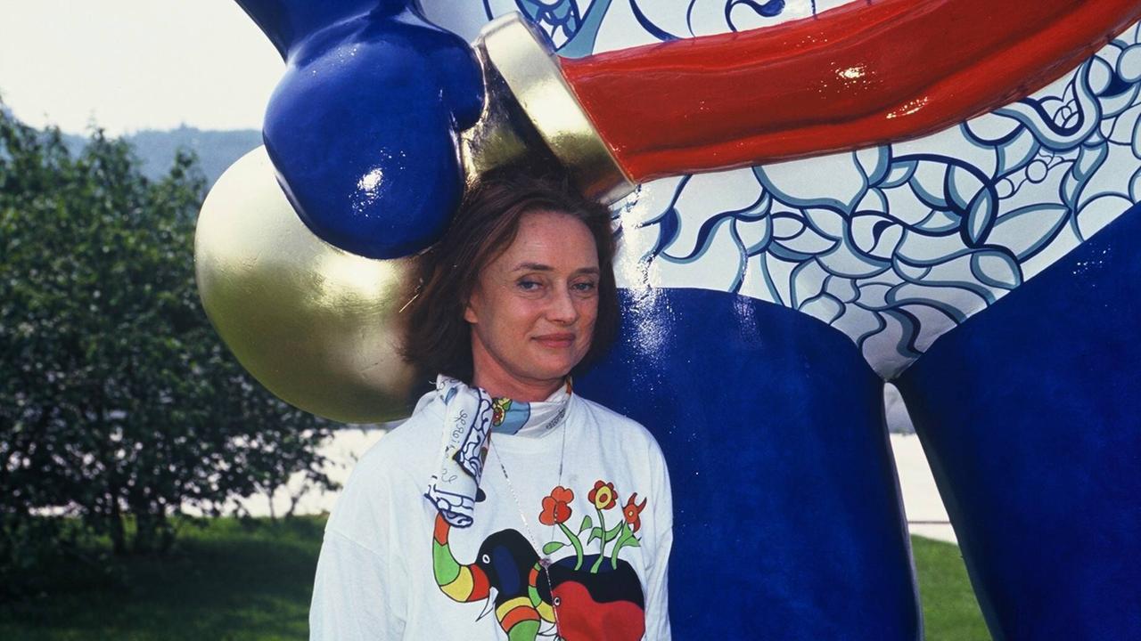 Eine Frau steht vor einer Kunstskulptur. Es istdike französisch-schweizerische Künstlerin Niki de Saint Phalle bei einer Ausstellung in Deutschland im Jahr 1992 Eine Frau steht vor einer Kunstskulptur. Es istdike französisch-schweizerische Künstlerin Niki de Saint Phalle bei einer Ausstellung in Deutschland im Jahr 1992