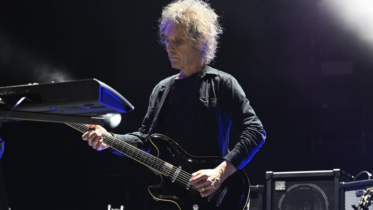 Der Musiker Perry Bamonte spielt mit ernster Miene und konzentriert wirkend bei einem Konzert auf seiner Gitarre. 