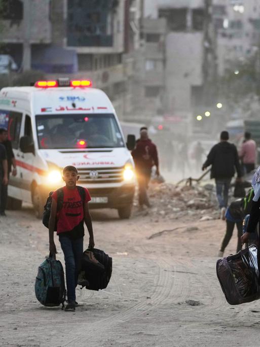 Mehrere Palästinenser fliehen aus Gaza-Stadt. Im Hintergrund ein Krankenwagen