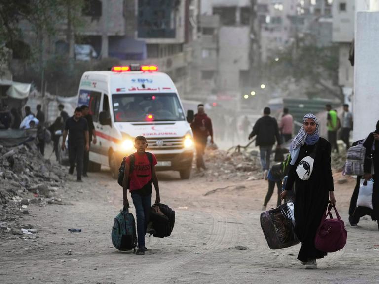 Mehrere Palästinenser fliehen aus Gaza-Stadt. Im Hintergrund ein Krankenwagen