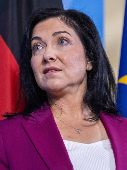 Wirtschafts- und Energieministerin Katherina Reiche trägt ein pinkes Jackett, im Hintergrund sind eine blaue Wand sowie die Deutschland- und die EU-Flagge zu sehen.
